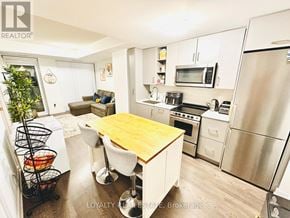 Toronto (Mimico) condo for rent - A kitchen with a wooden table and stainless steel appliances.