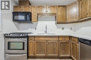 Guelph townhouse for rent - A kitchen with wooden cabinets and a stove top oven.