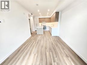 Coquitlam apartment for rent - A spacious room with wooden flooring and a kitchen area in the background.