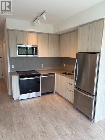 Milton (Cb Cobban) condo for rent - A modern kitchen with stainless steel appliances and wooden cabinets.