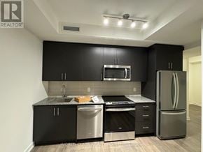 Oakville (Jm Joshua Meadows) condo for rent - A modern kitchen with black cabinets and stainless steel appliances.