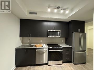 Oakville (Jm Joshua Meadows) condo for rent - A modern kitchen with black cabinets and stainless steel appliances.
