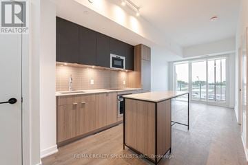 Mississauga (Port Credit) condo for rent - A modern kitchen with wooden cabinets and a microwave above the oven.