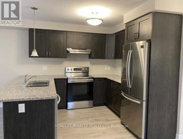 Kitchener townhouse for rent - A kitchen with a refrigerator, sink, and stove.