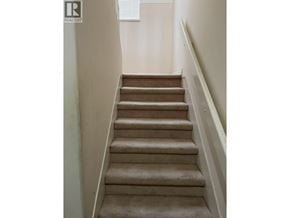 Richmond apartment for rent - A staircase with beige carpeted steps and white railings.