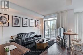Toronto (Waterfront Communities) condo for rent - A living room with a black leather sofa, a wooden coffee table, and a glass door leading to a balcony.