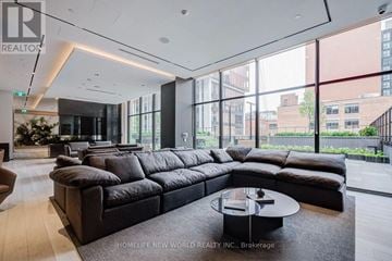 Toronto (Waterfront Communities) condo for rent - A large black sectional sofa in a modern living room.