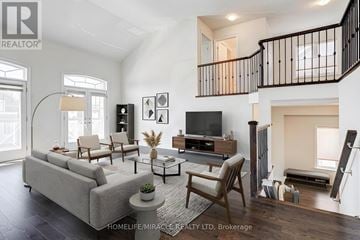 New Tecumseth (Alliston) apartment for rent - A living room with a grey sofa, a wooden chair, a television and a staircase.