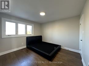 Mississauga (Erin Mills) apartment for rent - A bedroom with a black bed and wooden flooring.