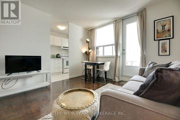 Toronto (Cabbagetown-South St. James Town) condo for rent - A living room with a brown couch and a television on a white stand.