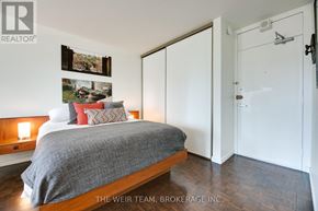Toronto (Cabbagetown-South St. James Town) condo for rent - A bedroom with a bed, pillows, pictures, and a wooden headboard.