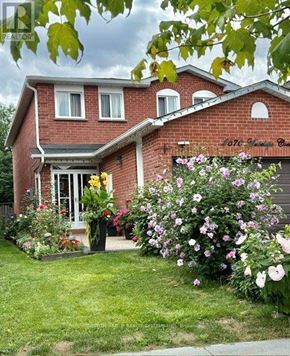 Mississauga (Hurontario) apartment for rent - A house with a red brick exterior and a white door surrounded by a garden with pink and white flowers.