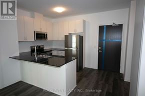 Oakville (Go Glenorchy) condo for rent - A kitchen with a black counter top and white cabinets.