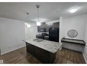 Edmonton apartment for rent - A kitchen with a black fridge and microwave, a white countertop, and a black oven.