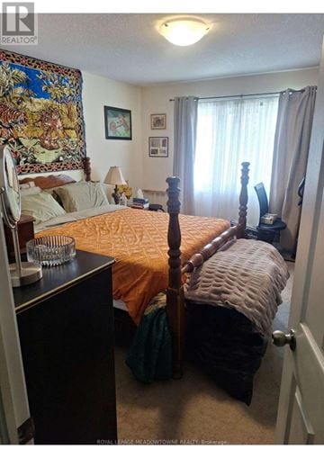 Brantford townhouse for rent - A bedroom with a bed, dresser, and a painting on the wall.