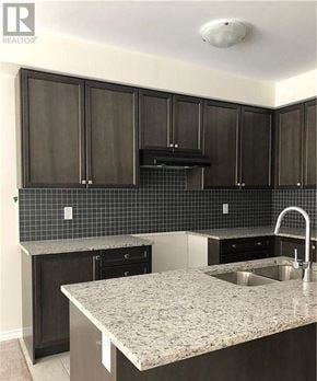 Niagara Falls (Brown) apartment for rent - A kitchen with dark wood cabinets and a granite countertop.