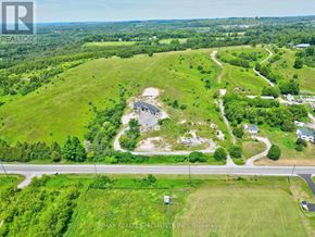 Cramahe apartment for rent - An aerial view of a large green field with a small building in the middle and a road running through it.