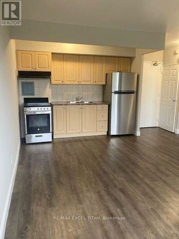 Hamilton (Corktown) condo for rent - A kitchen with wooden cabinets and a stainless steel refrigerator.