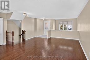 Ottawa townhouse for rent - A spacious room with wooden flooring and a staircase with a wooden railing.