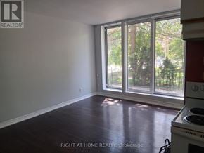 Toronto (Annex) multi-family for rent - A room with a stove and a window overlooking a fence.