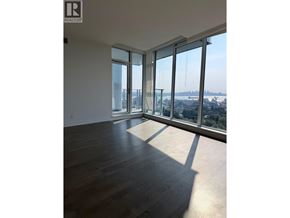 North Vancouver apartment for rent - A large empty room with a view of the city through the windows.