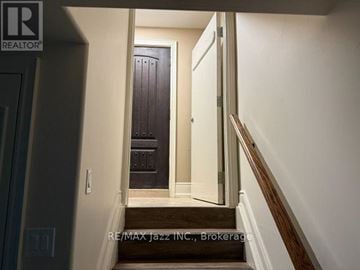Whitby (Blue Grass Meadows) apartment for rent - A hallway with a wooden staircase leading to a dark brown door.
