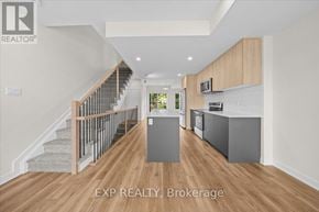 Ottawa townhouse for rent - A spacious room with wooden floors and a staircase with a metal railing.