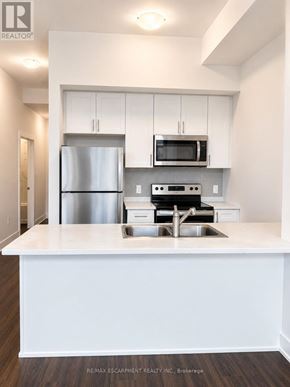 Hamilton (Waterdown) condo for rent - A white kitchen with a stainless steel refrigerator and microwave above the stove.