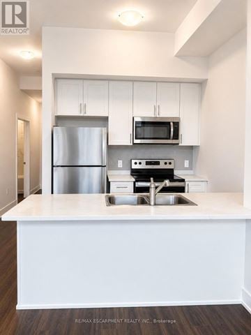 Hamilton (Waterdown) condo for rent - A white kitchen with a stainless steel refrigerator and microwave above the stove.