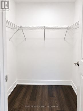Hamilton (Waterdown) condo for rent - A white closet with a wooden floor and a metal rack.