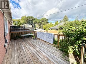 Richmond Hill (Crosby) apartment for rent - A wooden deck with a table and chairs is surrounded by greenery.