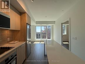 Toronto (Regent Park) condo for rent - A modern kitchen with wooden cabinets and a stainless steel refrigerator.