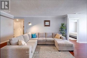 Toronto (Bendale) condo for rent - A living room with a grey couch and a small Christmas tree.