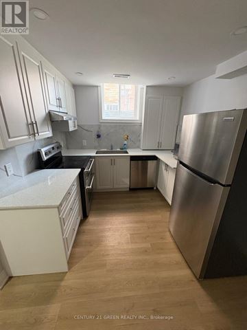 Brampton (Bram East) apartment for rent - A kitchen with white cabinets and a wooden floor.