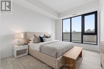 Toronto (Thorncliffe Park) condo for rent - A bedroom with a large bed, a nightstand with a lamp, and a window with a view of the city.