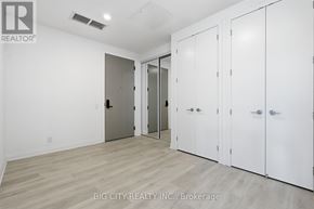 Toronto (Thorncliffe Park) condo for rent - A room with white walls and wooden flooring, featuring a set of white doors and a mirror.