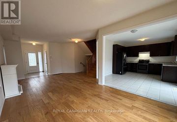 Brock (Beaverton) apartment for rent - A spacious living room with hardwood floors and a kitchen area in the background.
