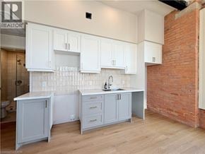 Hamilton apartment for rent - A kitchen with white cabinets and a brick wall.