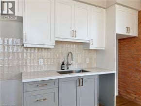 Hamilton apartment for rent - A kitchen with white cabinets and a brick wall.