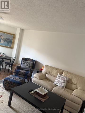 Brampton (Brampton West) townhouse for rent - A living room with a beige couch, a black coffee table, and a painting on the wall.