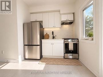 Toronto (University) apartment for rent - A kitchen with a stainless steel refrigerator and oven, white cabinets, and a window letting in natural light.