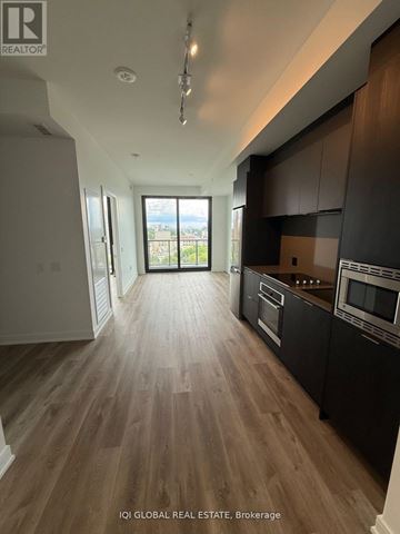 Mississauga (Cooksville) condo for rent - A modern kitchen with dark wood cabinets and a view of the city.