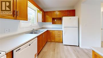 Sarnia townhouse for rent - A kitchen with wooden cabinets and white appliances.