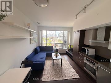 Toronto (Niagara) condo for rent - A well-lit living room with a blue sofa and a coffee table.