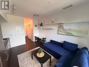 Toronto (Niagara) condo for rent - A living room with a blue couch and a painting on the wall.