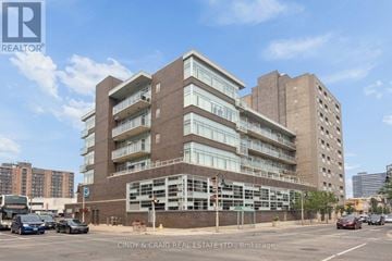 Oshawa (O'neill) condo for rent - A large brick building with many windows and balconies is the main focus of the image.