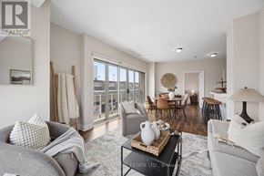 Oshawa (O'neill) condo for rent - A well-lit living room with a grey sofa, a coffee table, and a dining area in the background.