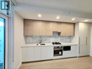 Burnaby apartment for rent - A modern kitchen with white cabinets and a wooden backsplash.