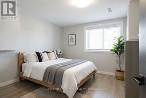 Oshawa (Donevan) apartment for rent - A bedroom with a bed, pillows, a blanket, a plant, and a framed picture on the wall.