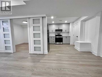 Pickering apartment for rent - A spacious kitchen with white cabinets and a wooden floor.